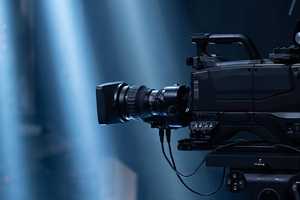 istock Professional broadcast camera capturing a live concert or event, recording performers on stage with dynamic blue lighting and dramatic stage light beams creating an immersive atmosphere 2253307248