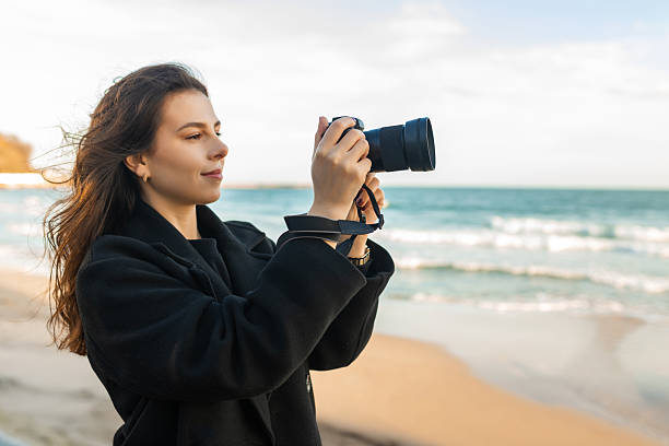 istock Smiling female photographer holding a camera on a 2253307424