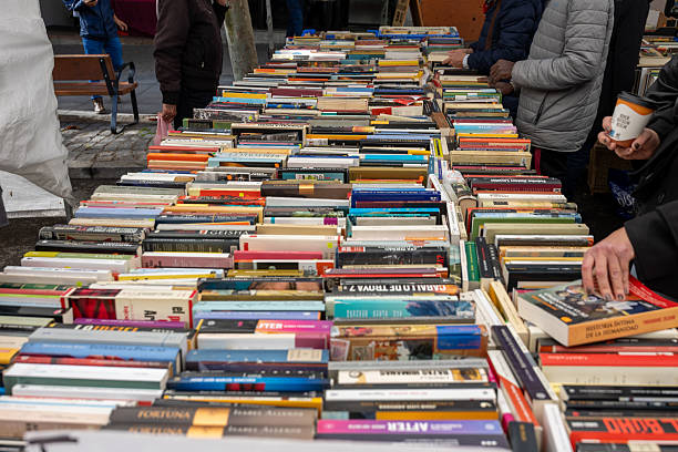 Madrid, spain; 11 15 2025 shoppers looking through piles of old books at an outdoor market stall in madrid