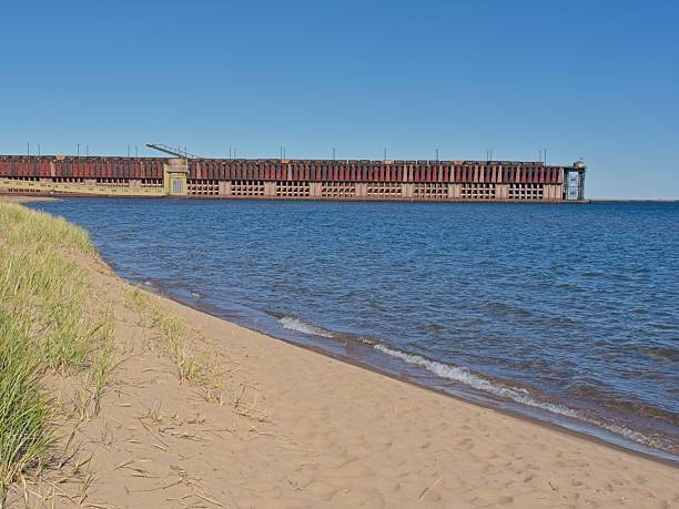 Freight trains load iron ore into shoots on ore dock for loading a massive Great Lakes shipping freighter