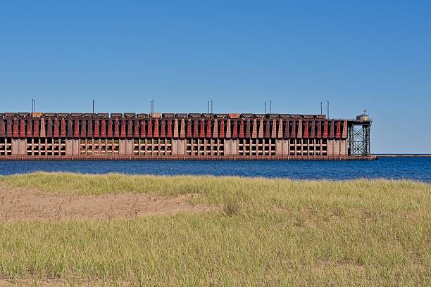 istock Freight trains load iron ore into shoots on ore dock for loading a massive Great Lakes shipping freighter 2253314218
