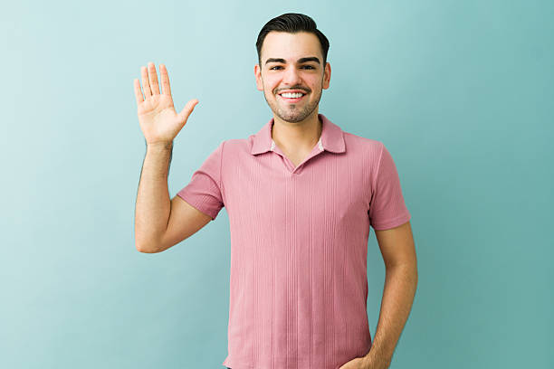 istock Friendly man standing, smiling broadly, and waving with an open hand, expressing a cheerful and welcoming greeting 2253317161
