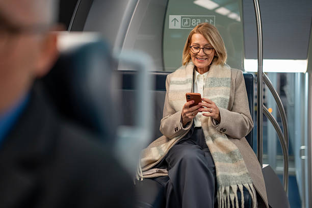 istock Senior woman smiling using phone on subway train 2253317242