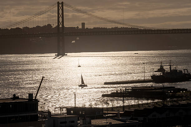 Lisbon Portugal December 06 2025. The 25 de Abril Bridge forms a silhouette above the shimmering waters of the Tagus River.