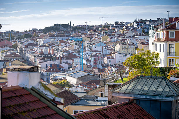 Lisbon Portugal December 06 2025 Elevated view of dense Bairro Alto housing with rooftops a construction crane and hillside buildings
