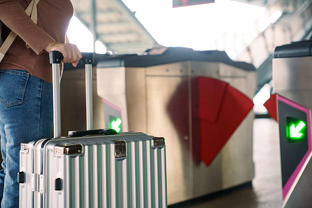 Traveler pulling suitcase through automatic gate at modern train station. Concept of public transportation, urban mobility, commuting process, travel logistics and smooth transit in smart city lifestyle.