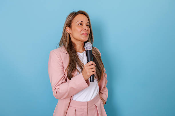 istock Woman presenter holding microphone feeling confident while speaking during a public speech or conference 2253321654