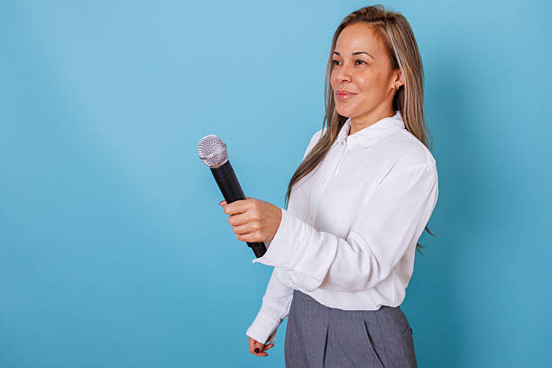 istock Female journalist holding microphone asking questions during interview, broadcasting news against a blue background 2253325099