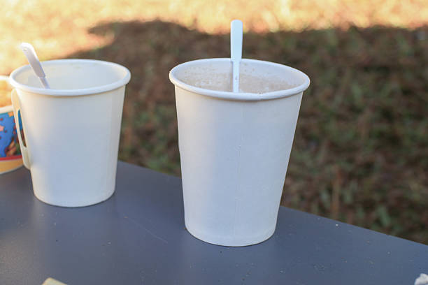 Paper cup with red and white straw on white background. Takeaway disposable paper cup