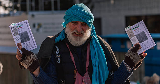 Davos, Switzerland – January 21, 2025: Bearded man wearing a blue headscarf holds printed leaflets reading “ARARE Davos 2025” while standing on a city street.