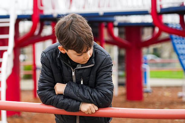 Crestfallen Concerned child boy looking down at a park playground