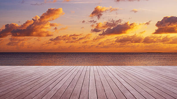 istock Empty wooden platform beside tropical sea shore with dramatic sky and clouds during the sunset 2253332404