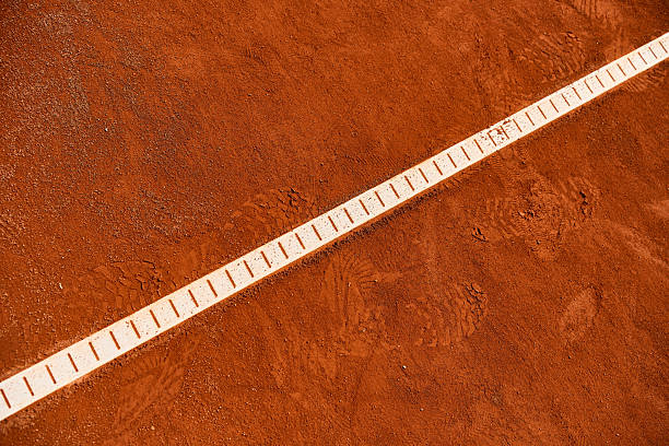 Yellow tennis ball strikes the red clay court with dust rising, close to a foot and racket in 3D environment. Concept of precision and focus for executive decision-making and leadership training