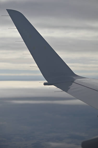 Airplane wing against cloudy sky during flight.