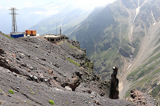 istock Rocky mountain landscape with building under construction and power line pylon 2253346758