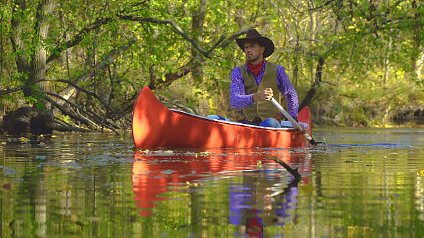 istock Cowboy in a canoe floats on the river in the forest 2253347196
