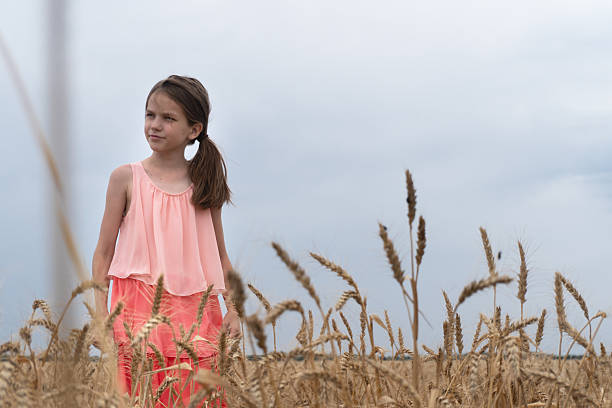 Girl in a field with yellow wheat against a cloudy sky