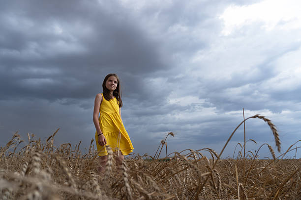 Girl in a ripe wheat field against a cloudy sky. Harvest season