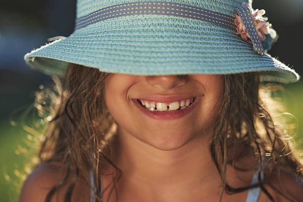 A serene woman in a summer hat smelling a bouquet of wildflowers, embodying leisure and the joy of a warm, sunny day.