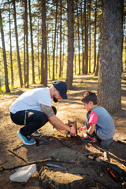 istock Father And Son Camp Outdoors Building A Fire Pit In Forest During Family Camping Together 2253352986
