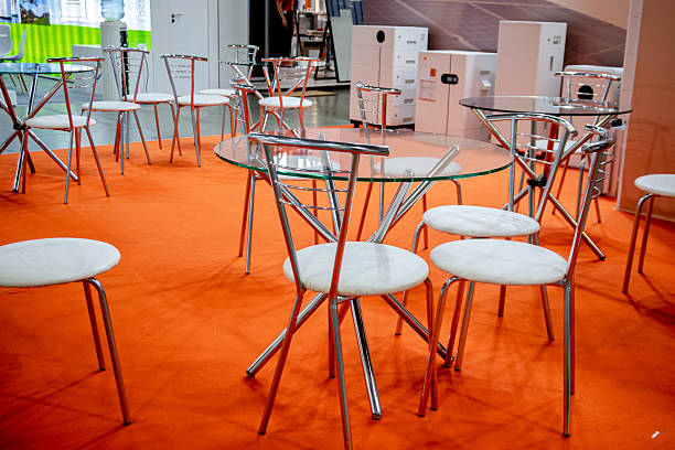 istock Modern glass tables and chrome chairs on a vibrant orange carpet create a contemporary lounge area at an exhibition. Ideal for business, events, or interior design concepts. 2253354251