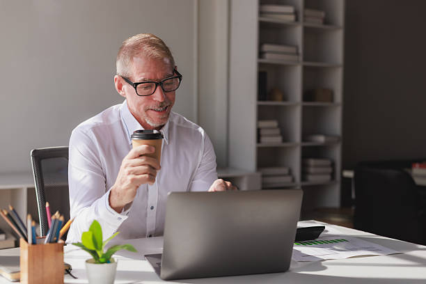 istock Mature businessman drinking coffee working on laptop 2253355278
