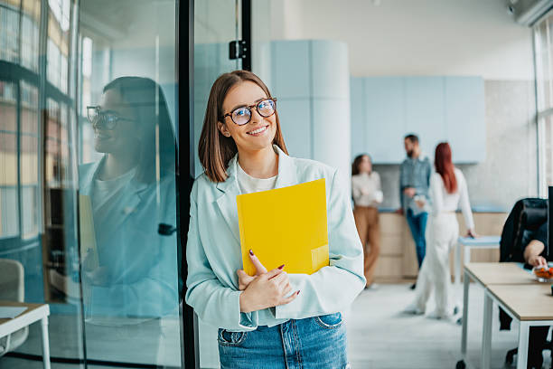istock People working together inside an office space during daytime, with one person holding files and smiling at the camera 2253356540