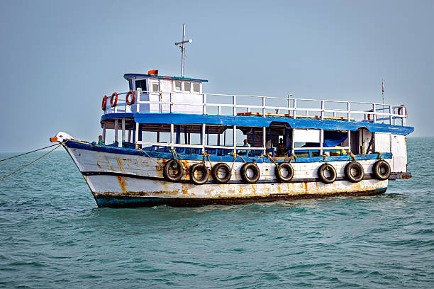 Passenger ferry boat floating on calm sea under clear blue sky, India.