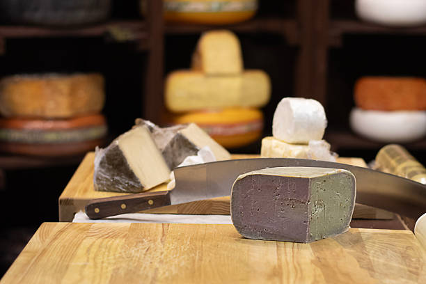 istock Assorted cheese blocks and knife on wooden board in a rustic cheese shop display 2253357771