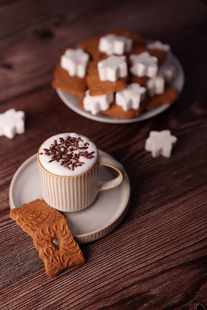 cozy setting with a cup of coffee adorned with chocolate sprinkles, paired with intricately designed cookies on a saucer, set against a wooden backdrop with marshmallow accents, inviting, soft