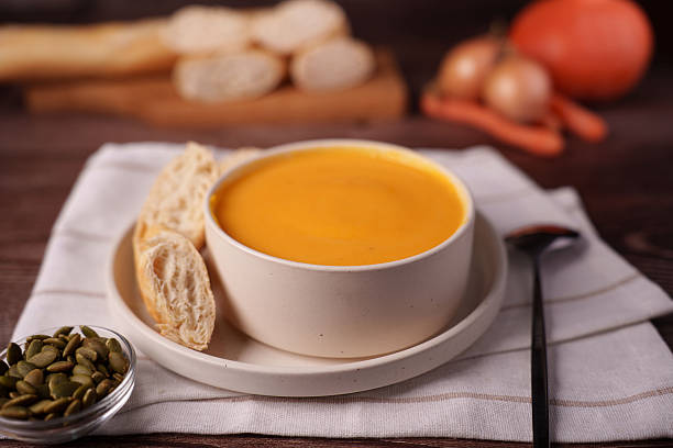 warm autumn scene with creamy pumpkin soup, crusty baguette, and fresh vegetables on a rustic wooden table in soft warm lighting, background, blurred, soft, texture, smooth, round, palette, inviting