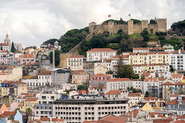 Lisbon, Portugal - June 21, 2019: As the late afternoon sun casts a soft light over Lisbon, the houses climb the slope of Castelo de São Jorge, leading up to the historic castle at the hill’s peak.