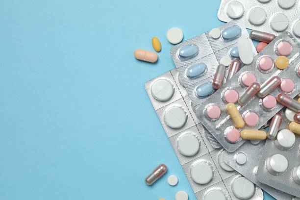 istock Pills in blister packs on blue background, close up 2253370283