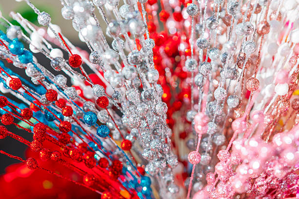 Shimmering beaded garlands in vibrant holiday colors, against soft background. Glossy beads evoke festive Christmas ambiance. Various strands of glitter floral picks featuring beaded accents