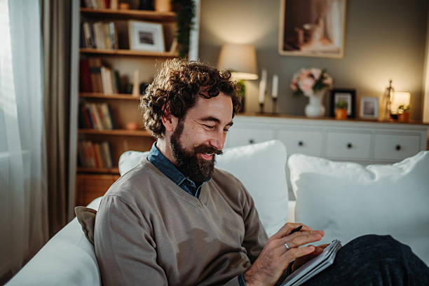 istock Man writing notes smiling in comfortable living room 2253373727
