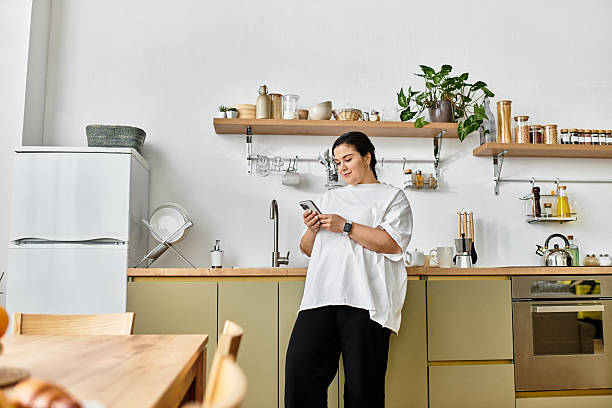 istock Beautiful plus size woman relaxed at home, enjoying her time with a smartphone while cooking 2253375331