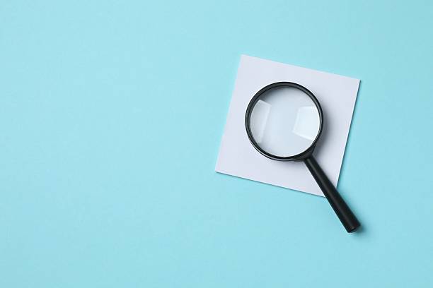 istock Magnifying glass with paper stickers on blue  background 2253375468