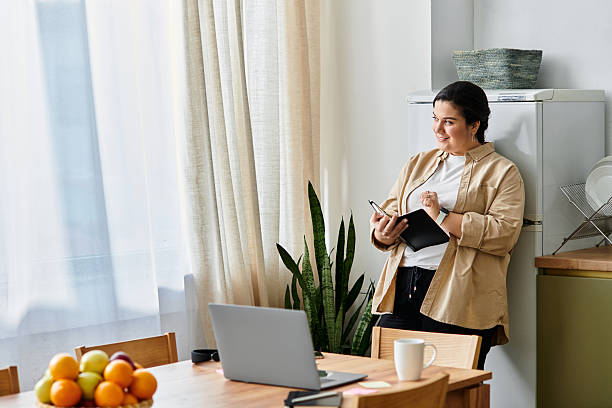 istock Beautiful plus size woman enjoying a cozy moment at home while taking notes 2253375687