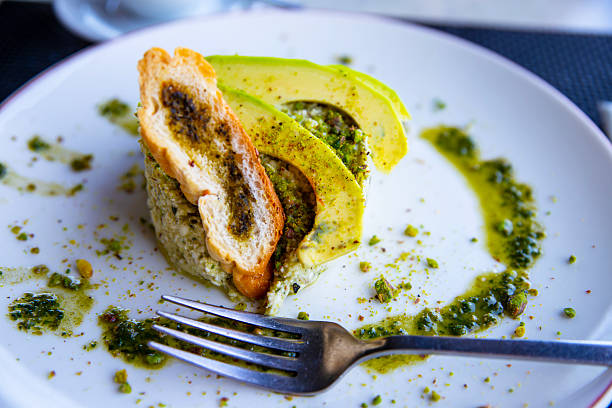 Chicken chest with avocado in Basil sauce on a white plate