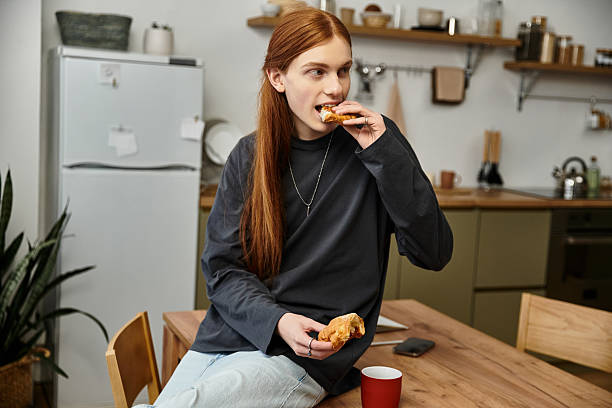 istock Handsome young man enjoys a tasty pastry while relaxing at home in a cozy kitchen setting 2253377475