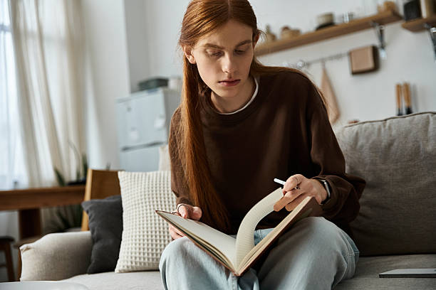 istock Handsome young man immersed in reading on a cozy couch in a stylish home setting 2253377518