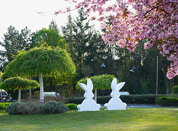 White figures of rabbits on the grass in a spring garden are Easter decorations.