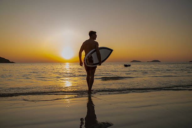 istock Silhouette Young man entering the ocean at sunset while holding surfboard expressing freedom and an adventurous beach lifestyle outdoor sports personal growth and inspirational summer lifestyle. 2253379061