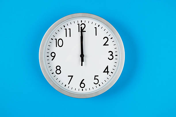 istock Mechanical clock showing midnight or noon at 12:00 on blue background. 2253384660
