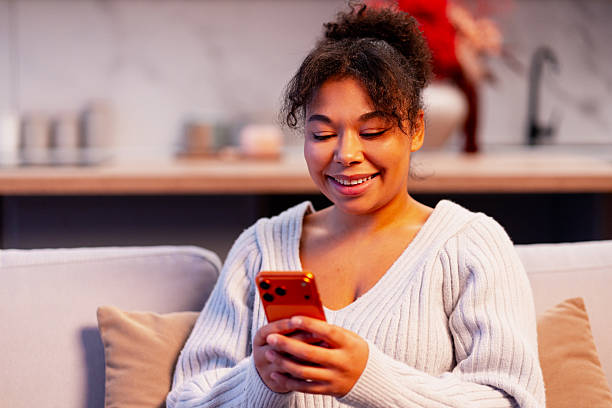 istock Young woman smiling while using phone, enjoying social media and connection at home 2253387910