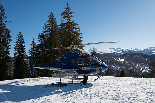 istock A blue helicopter awaits on a snowy mountain, ready for heli-skiing. Surrounded by pine trees and stunning alpine scenery under a clear blue sky, it captures the essence of winter adventure 2253389853