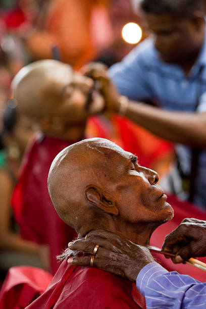 Men having their heads shaved as a traditional offering during the Hindu religious festival of Thaipusam.