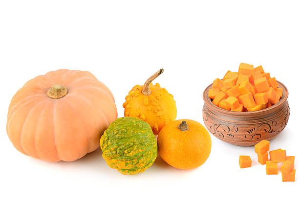 istock Whole pumpkins and a ceramic bowl with orange pumpkin cubes isolated on white. 2253392030