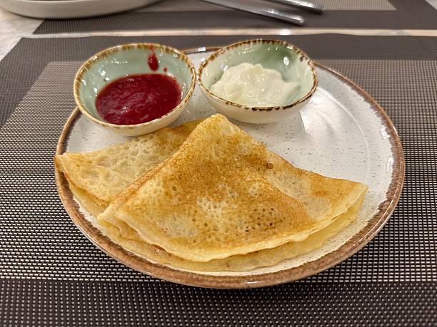 istock Crepes with sour cream and raspberry sauce served on plate in dining setting 2253393616