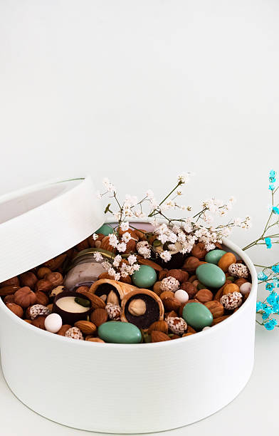 On a light background there is a round box filled with various nuts and dried fruits. Mothers Day. Valentine's Day. International Women's Day.A delightful gift. Low-fat food.